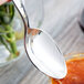 A Libbey stainless steel dessert spoon holding red sauce over a bowl.