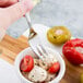 A Libbey stainless steel cocktail fork in a bowl of mozzarella cheese and tomatoes.