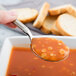 A Libbey stainless steel bouillon spoon holding soup over a slice of bread.