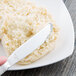 A person uses a Libbey stainless steel bread and butter knife to spread butter on a biscuit.