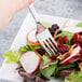 A Libbey stainless steel salad fork in a vegetable salad.