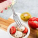 A Libbey stainless steel cocktail fork in a bowl of mozzarella cheese and tomatoes.