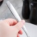 A hand holding a Libbey stainless steel dinner fork over a plate.