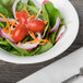 A Schonwald Avanti Gusto bowl of salad with tomatoes, spinach, and onions on a table.