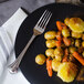 A World Tableware Resplendence dinner fork on a plate of food with potatoes and carrots.