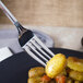 A World Tableware Resplendence dinner fork on a plate of food with potatoes.