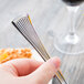 A person holding a Libbey stainless steel utility/dessert fork.