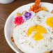 A Schonwald Marquis white porcelain bowl filled with food on a table with flowers.