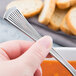 A person holding a Libbey stainless steel bouillon spoon over a bowl of soup.