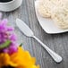 A Libbey stainless steel butter spreader on a plate with biscuits.