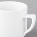 A close-up of the handle of a white Schonwald stacking mug.