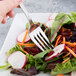 A Libbey stainless steel salad fork in a vegetable salad on a plate.