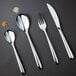 A Chef & Sommelier stainless steel dinner spoon on a black surface.