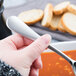 A person using a Reserve by Libbey stainless steel bouillon spoon to eat soup.