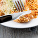 A stainless steel knife and fork on a plate of food.