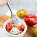 A Reserve by Libbey stainless steel cocktail fork in a bowl of mozzarella cheese and tomatoes.