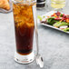 A white cup of iced tea with a Libbey stainless steel iced tea spoon.