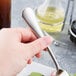 A hand holding a Reserve by Libbey stainless steel salad fork over a plate of food.