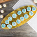 A gold rectangular Thunder Group tray with cupcakes on a table.