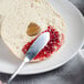 A person using a Master's Gauge stainless steel butter spreader to spread jam on a bagel.