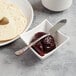 A bowl of jam with a Master's Gauge butter spreader next to a bagel.