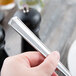 A person holding a Libbey Vermont stainless steel serving spoon over a plate of food.