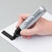 A hand using a Sharpie Magnum black chisel tip permanent marker to write on paper.