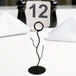 A white table number on a black branch card holder on a table.