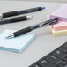 A Uni-Ball Signo 207 blue gel pen next to post-it notes on a desk.