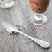 A Master's Gauge stainless steel dessert spoon next to a glass of chocolate milk on a table.