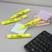 A black keyboard and a group of Sharpie yellow highlighters.