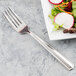 A Libbey stainless steel salad fork next to a plate of salad.