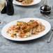 A Villeroy & Boch white porcelain oval plate with rice and meat on it on a table.
