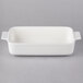A white rectangular porcelain baking dish with black handles.