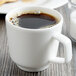 A white porcelain cup of coffee on a table.