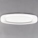 A Villeroy & Boch white porcelain oval platter with a curved edge on a gray surface.