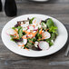 A plate of salad with radishes, carrots, lettuce, and cheese.