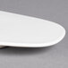 A close-up of a Villeroy & Boch white porcelain oval plate with a curved edge.