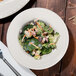 An Ivory china bowl filled with broccoli and carrots.