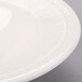 A close-up of an ivory china bowl with an embossed rim.