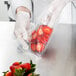 A gloved hand using a VacPak-It chamber vacuum packaging bag to hold strawberries.