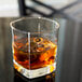 A Libbey Quartet double old fashioned glass of whiskey with ice on a table.