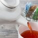 A Villeroy & Boch white porcelain teapot pouring tea into a cup.