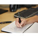 A hand holding a Uni-Ball Signo 207 pen and writing on a notebook.