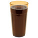 A Cambro Newport amber plastic tumbler filled with dark liquid with a yellow rim.