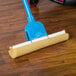 A blue mop refill with a blue sponge on a wooden floor.
