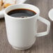 A Villeroy & Boch white porcelain mug filled with coffee on a table.