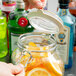 A person pouring orange slices into an Anchor Hocking Hermes jar.