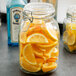 An Anchor Hocking Hermes jar filled with lemon slices on a bar counter.
