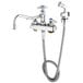 A chrome T&S deck-mounted workboard faucet with a hose and spray nozzle.